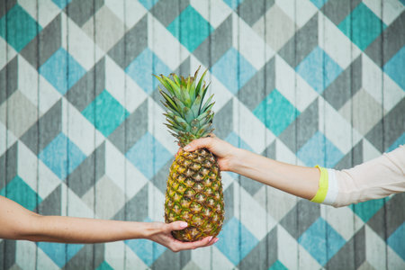 Two female hands hold pineapple together. Giving the best concept, togetherness and friendship.