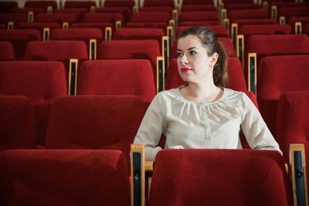 Young woman watch show in theater or cinema empty auditorium enjoy play on stageの写真素材