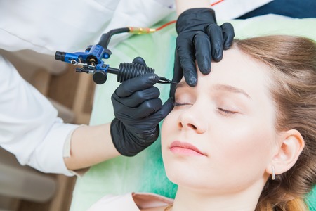 Cosmetologist applying permanent makeup on browsの写真素材