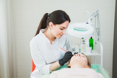 Female cosmetologist with manual tattoo pen machine applying permanent make-up with microblading techniqueの写真素材