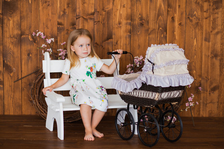 Pretty little girl play with retro pram, child with baby strollerの写真素材