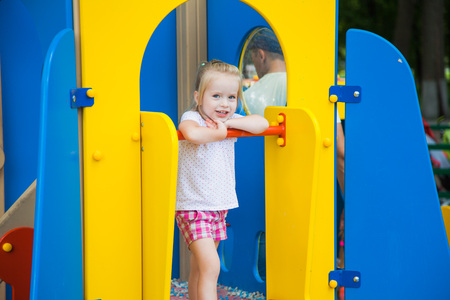 Cute little girl on a colorful playground on a sunny summer dayの写真素材