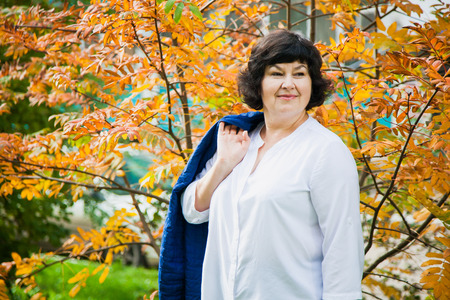 Beautiful middle aged woman in yellow leaves.の写真素材