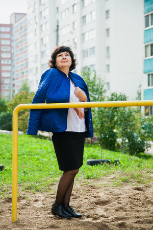 Middle aged woman among city apartment buildingsの写真素材