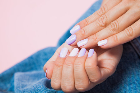 Beautiful female wrist with nail manicure closeup. Denim jeans background