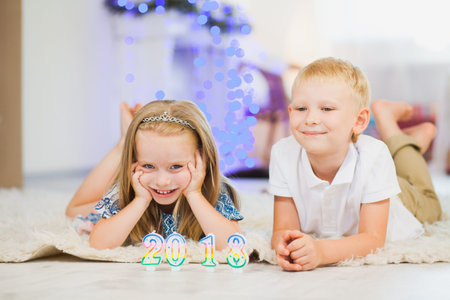 Little sister and brother play new year candles 2018. Two children waiting for santa. Christmas preparation, happy familyの写真素材