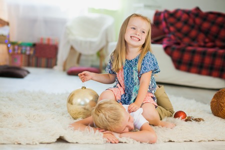 Cute girl and boy play with new year toys. Brother and sister have fun at home before xmas eve. Family christmas tree decorationの写真素材