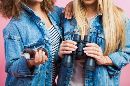 Two attractive women in jeans jackets with sunglasses and binoculars. Closeup shot without faces. Travelling and vacation conceptの写真素材