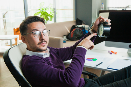 Office worker young businessman hold alarm clock time management conceptの写真素材