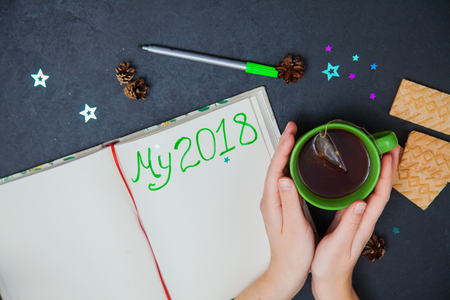 Writing plans for new year my 2018 to do list. Female hand holding marker, green cup of tea, cookies, pine cone の写真素材