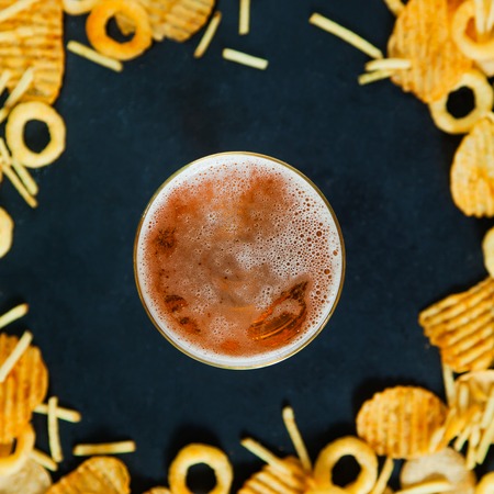 Fast junk food concept onion rings french fries potato chips beer snack unhealthy nutrition. Background with copy space square.の写真素材