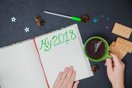 Writing plans for new year my 2018 to do list. Female hand holding marker, green cup of tea, cookies, pine coneの写真素材