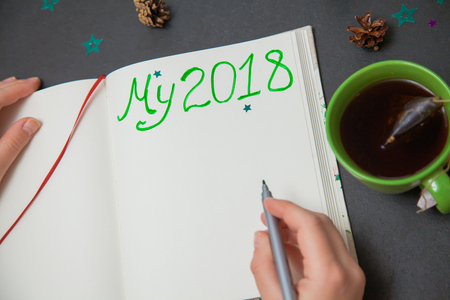 Writing plans for new year my 2018 to do list. Female hand holding marker, green cup of tea, cookies, pine coneの写真素材