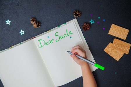 Little child writing letter to Santa Claus on a blank sheet of paper. Small hands of a girl holding marker. Christmas preparation concept.の写真素材