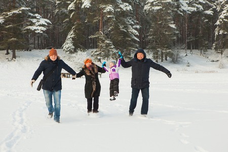 Beautiful happy family running together on sunny winter day.の写真素材