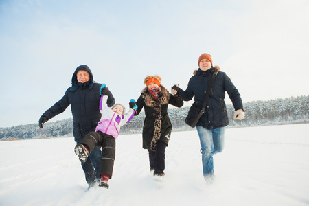 Beautiful happy family running together on sunny winter day.の写真素材