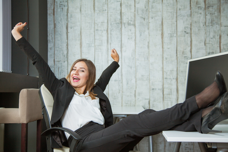 Happy business woman sitting in a boss armchair and smile. Goal reached, job done. Successful business conceptの写真素材