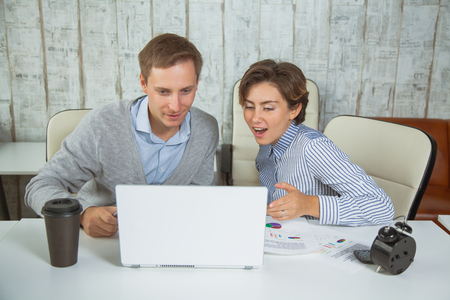 Two office workers team job lap top cooperation students. Young man and woman point at computer monitorの写真素材