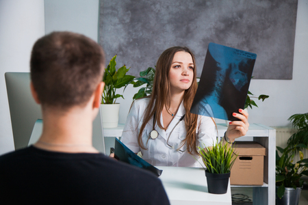 Young professional female doctor examining patient's x-ray of human scull during a visit. Health medicine conceptの写真素材