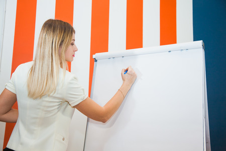 Portrait of young businesswoman giving presentation to colleagues. Young woman showing new design layout on white board to coworkers during business presentation.の写真素材