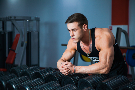Fit male athlete getting ready for dumbbell workout. Handsome man at fitness gym take rest and breathe. Fitness, bodycare and active lifestyle concept.の写真素材