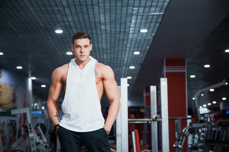 Handsome guy at fitness gym pose to camera. Fit muscular man with perfect body gets ready for workout. Fitness, bodycare and active lifestyle concept.の写真素材