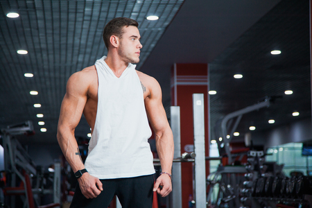 Handsome guy at fitness gym pose to camera. Fit muscular man with perfect body gets ready for workout. Fitness, bodycare and active lifestyle concept.の写真素材