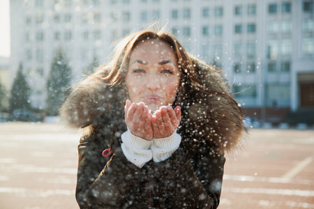 Young woman blow the snow from her hands. Winter, christmas and people concept.の写真素材