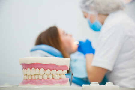 Defocused, blurred image of dentist with patient at clinic office. Stomatologist making tooth...