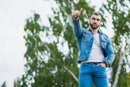 Handsome athletic fit man in jeans wear fitness model outdoors copy space. Young male with perfect muscular body poses to cameraの写真素材