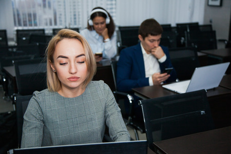Female adult student concentrated on studying. Woman using laptop with group of people on background. Education conceptの写真素材