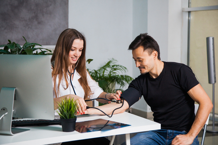 Female doctor measuring arterial blood pressure, for patient on old tonometer at clinic. Health care and physician conceptの写真素材
