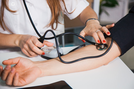 Female doctor measuring arterial blood pressure, for patient on old tonometer at clinic. Health care and physician conceptの写真素材