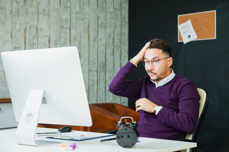 Confused disappointed businessman look at computer screen at office. Failure conceptの写真素材