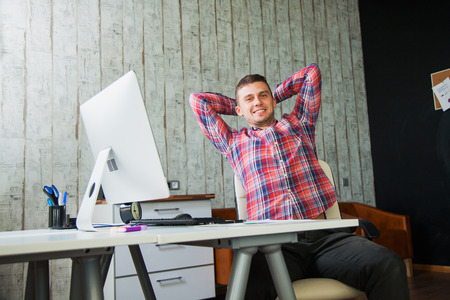 Young happy man satisfied with result of work. Male office worker smile after finishing business task.の写真素材