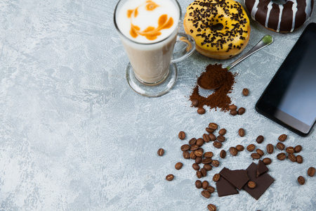 Latte coffee arabica espresso beans donuts dark chocolate background. Time for coffee and smartphone socail net concept.の写真素材