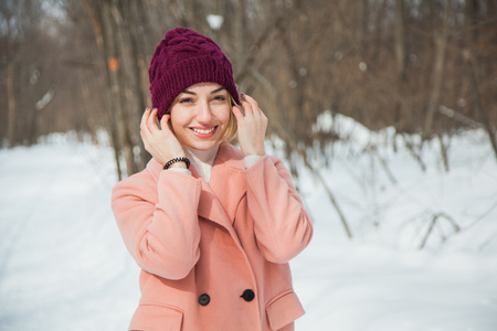 Beautiful happy woman in hand knitted hat outdoors on cold snowy winter day. Cozy warm clothes, frosty weather, copy space.の写真素材