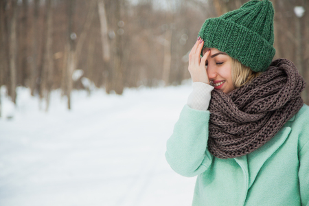 Beautiful happy woman in hand knitted hat outdoors on cold snowy winter day. Cozy warm clothes, frosty weather, copy space.の写真素材