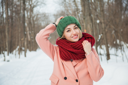 Beautiful happy woman in hand knitted hat outdoors on cold snowy winter day. Cozy warm clothes, frosty weather, copy space.の写真素材