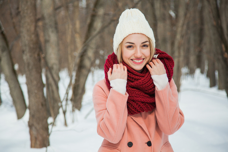 Beautiful happy woman in hand knitted hat outdoors on cold snowy winter day. Cozy warm clothes, frosty weather, copy space.の写真素材
