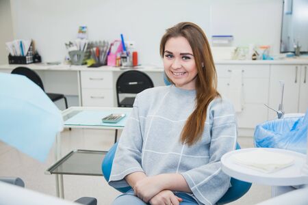 Satisfied female dentist patient after treatment in a clinic box with medical equipment in the backgroundの写真素材
