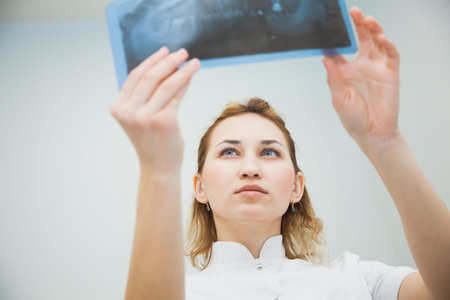Female doctor dentist examining x-ray of human jaw. Professional stomatologist checking dental x-ray...