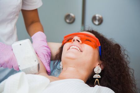 Laser hair removal, photoepilation, body and skin care concept. Young woman remove hair on legs at cosmetology clinic.の写真素材