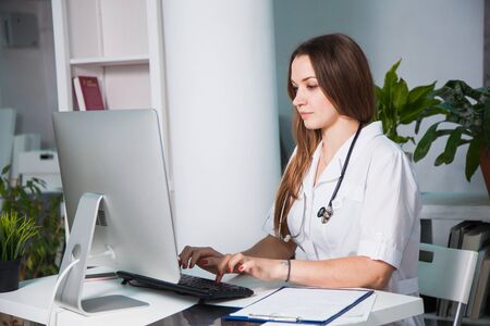 Female doctor consulting patient online from clinic office. Giving medical advise and prescriptions by internet. Pandemic coronavirus, isolation, keeping distance concept.の写真素材