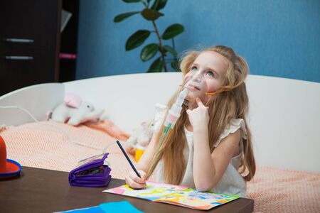 Cute little girl draw and breathe inhaler to prevent virus respiratory symptoms. Child stay at home for quarantine on pandemic.の写真素材
