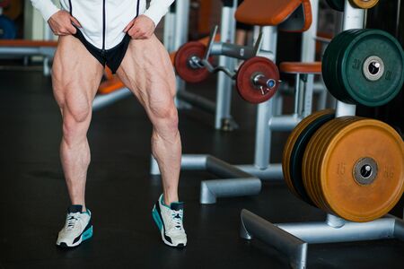 Male muscular athlete bodybuilder show thigh muscles. Strong unrecognized man at gym demonstrate legs muscularityの写真素材