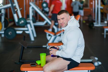 Bodybuilder with whey protein at modern gym. Male muscular athlete getting ready for hard workout with dumbbells equipment.の写真素材