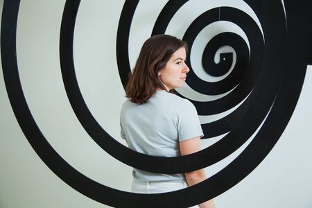 Serious woman in black spiral stand turned away. Female person at studio.の写真素材