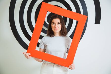 Young beautiful woman in casual clothes posing with red frame.の写真素材