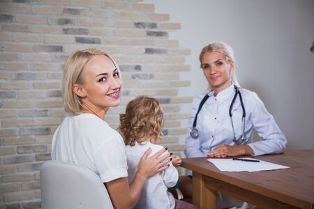 Professional medical pediatrician doctor in white uniform consult mother with her daughter. Pediatrist with kid patient good relationship trust conceptの写真素材